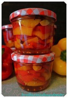 three jars filled with pickled fruit sitting on top of a table