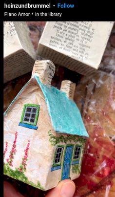 a small house made out of paper sitting on top of a table next to books