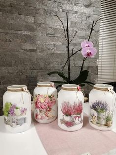 three vases with flowers painted on them sitting on a table next to a plant