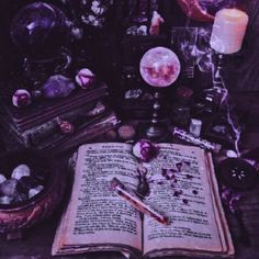 an open book sitting on top of a wooden table next to candles and other items