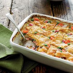 a casserole dish with meat, vegetables and gravy in it on a wooden table