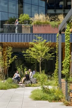 several people sitting on benches in front of a building with plants growing all over it