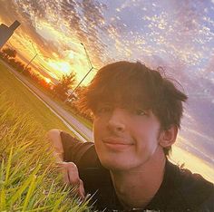 a man laying in the grass at sunset