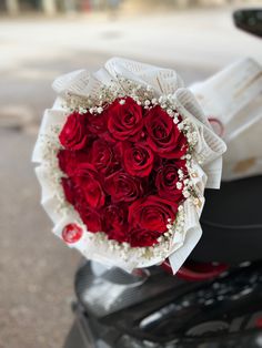 a bouquet of red roses sitting on the back of a motorcycle