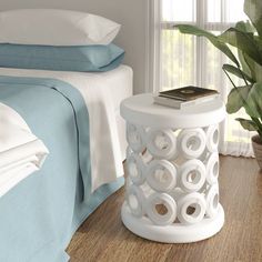 a white table sitting on top of a wooden floor next to a bed