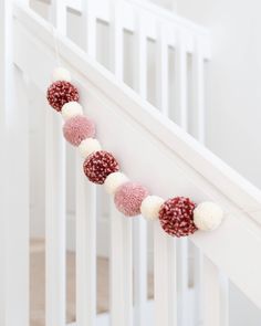 a white crib with pink and white pom - poms hanging from it