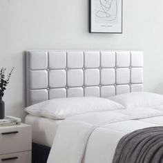 a bed with white sheets and pillows on top of it next to a night stand