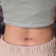 a woman's stomach with the word muse tattooed on her lower side ribcage