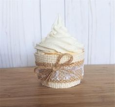 a cupcake wrapped in burlap and tied with a bow sits on a wooden table