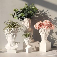 three white vases with plants in them on a table