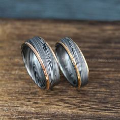 two silver and gold wedding bands with wood inlays on wooden table, close up