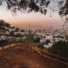 a view of a city from the top of a hill with a fence in front of it