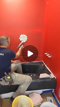 a man is painting a red wall with white paint