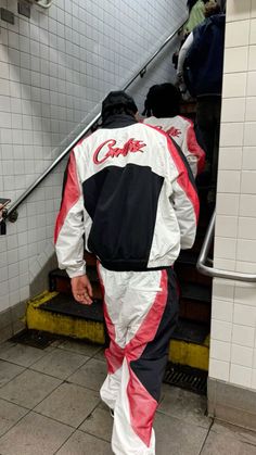 a man walking up an escalator with his foot in the air while wearing a racing suit