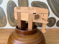 a wooden sculpture sitting on top of a brown vase