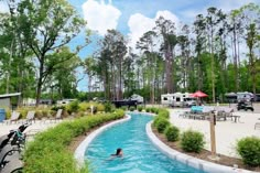 a person swimming in a small pool next to trees and camping trailers on the other side