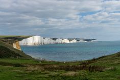 some white cliffs are in the water and green grass