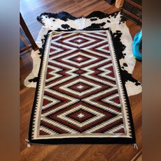 a black and white area rug on the floor next to a chair with a cow hide