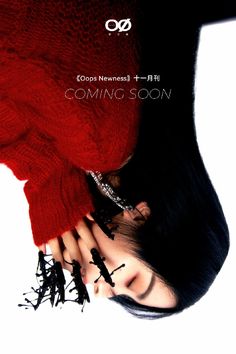 a woman with long black hair is wearing a red sweater and has her hands on her face