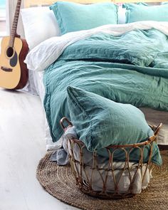 a bedroom with a guitar on the bed and a basket in the floor next to it