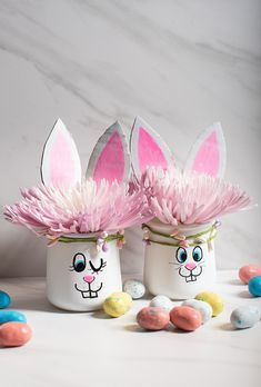 two easter eggs decorated with bunny ears and pink flowers in front of candy candies