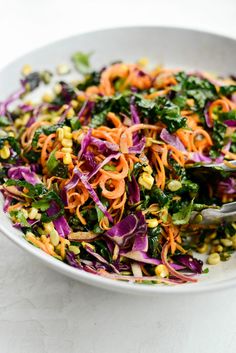 a white bowl filled with colorful vegetables on top of a table