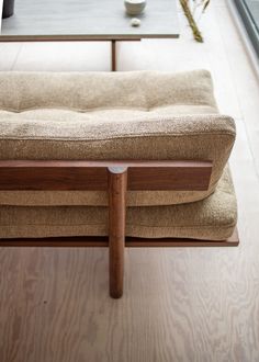 a wooden bench sitting on top of a hard wood floor next to a glass window