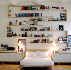 a bed sitting in a bedroom next to a wall filled with books