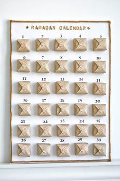 a wall calendar with numbers on it in gold foil and white paper, next to a fireplace