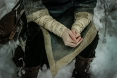 a person sitting in the snow with their hands on his knees and one hand wrapped around them