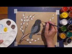 someone is painting a bird on a tree branch