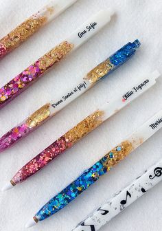 four pens with glitter on them are lined up