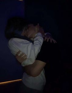 a man and woman kissing in the dark with their arms around each other as they hug