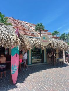 people are standing in front of a store with surfboards hanging from it's roof