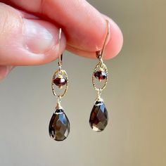 Smokey Topaz and Garnet Teardrop Earrings, Brown and Red Statement Earrings in Gold Filled, Elongated Drop Earrings, Fall Color Gift for her These golden fall color earrings feature faceted smokey topaz teardrops wire wrapped in your choice of gold filled or sterling silver. The dark brown drops are suspended from oval textured links with a red garnet rondelle suspended from it. The earrings are suspended from lever back ear wires.  These fall color earrings are perfect to match multiple outfits Smokey Topaz Earrings, Garnet Teardrop Earrings, Red Statement Earrings, Ears Pierced, Pretty Accessories, Silver Gift Wrap, Earrings Fall, Multiple Outfits, Brown Earrings