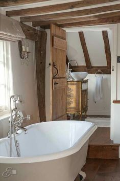 an old fashioned bathtub is in the middle of a room with exposed wood beams