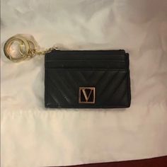 a black purse with a gold v on the front and a key chain attached to it