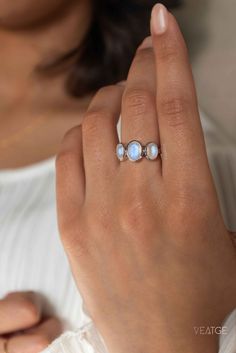 a woman wearing a ring with three stones on it