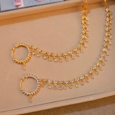 two gold necklaces and a pair of earrings are on display in a jewelry box