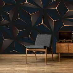 a black chair sitting in front of a wall with gold geometric designs on it's sides