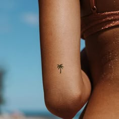 a woman with a small palm tree tattoo on her left arm and right arm behind her back