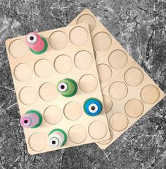 two wooden board game pieces with eyeballs on them sitting on top of a marble surface