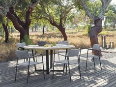 an outdoor table and chairs on a wooden deck with trees in the backround