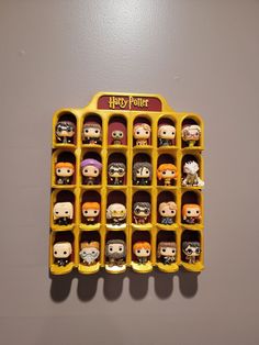 an assortment of harry potter figurines in a display case on a gray wall