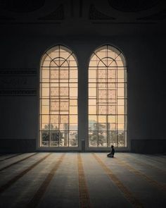 a person sitting on the floor in front of two large windows