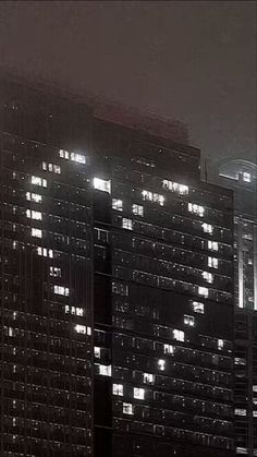 the building is lit up at night in the foggy city lights shine brightly on the skyscrapers