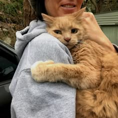 a woman holding an orange cat in her arms