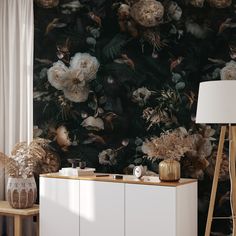 a white cabinet sitting next to a wall covered in flowers