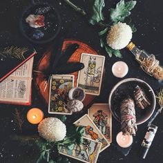 an arrangement of tarot cards, candles, and flowers on a table with other items