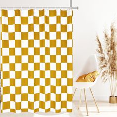 a yellow and white checkered shower curtain next to a chair with a plant in it